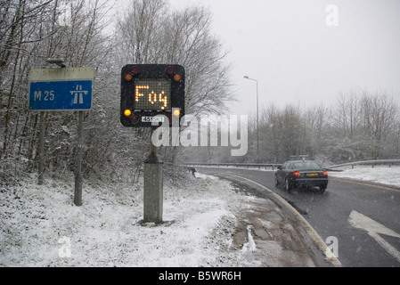 Junction 8 M25 Motorway in the Snow with a Fog Road traffic Sign uk in the winter Stock Photo