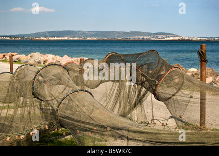 Fishing nets drying on the shores of the Bassin de Thau lagoon with Sete in the background. Stock Photo