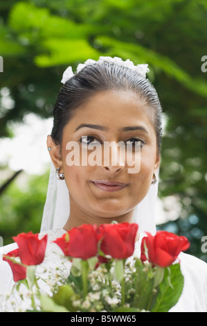 Portrait of a newlywed bride holding a bouquet of flowers and smiling Stock Photo