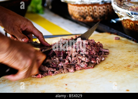 Detail of cooks hands as he chops meat with knife on a cutting board in a street cafe, San Felipe, Baja California, Mexico Stock Photo
