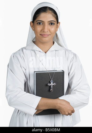 Portrait of a nun standing with her arms crossed and holding the Bible Stock Photo