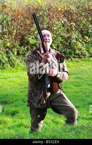 huntsman with shotgun looks skywards at beaten flying pheasant from a driven game bird shoot South Devon England UK Stock Photo