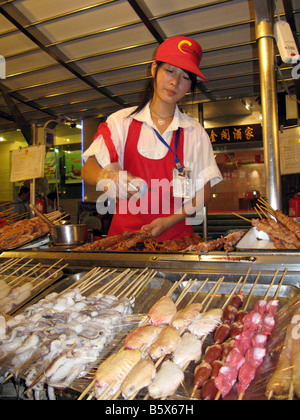 Young women serving food at Donganmen night Market stall in Beijing Stock Photo