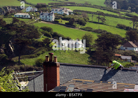 A roofer on a high roof with the Devon countryside behind Stock Photo