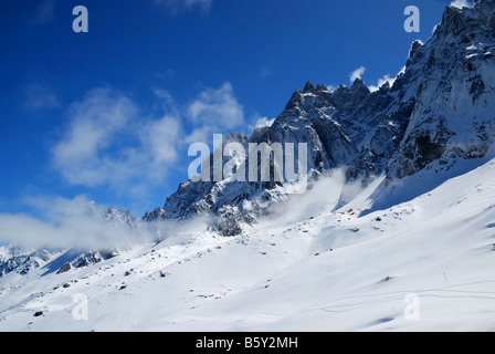 Steep peaks in light clouds and snow slopes against blue sky the Alps Mont Blanc France Stock Photo