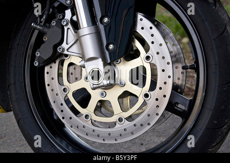 Closeup detail of a racing motorcyle s front wheel This is the brake caliper rotor rim tire and suspension Stock Photo