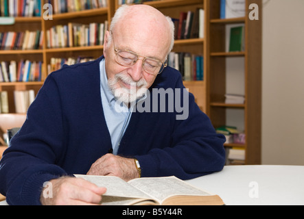 Senior man enjoys a good book in the library Horizontal view with room for text Stock Photo