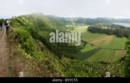 Tourists enjoying the view of Sete Cidades from the narrow road on the crater edge from Visto do Rei, going west, São Miguel Stock Photo