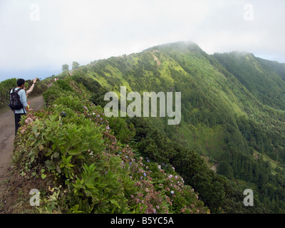 Tourists enjoying the view of Sete Cidades from the narrow road on the crater edge from Visto do Rei, going west, São Miguel Stock Photo