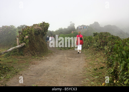 Tourists walking on the narrow road on the crater edge from Visto do Rei, going west, Sete Cidades, São Miguel, Azores. Stock Photo