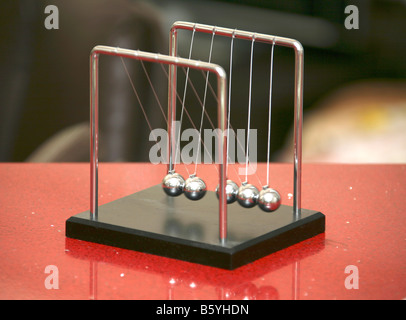 Newton’s Cradle game on red table Stock Photo