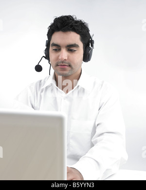 asian man working on his laptop wearing his headphones Stock Photo