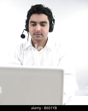 asian man working on his laptop wearing his headphones Stock Photo