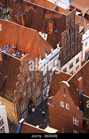 Person walking between mediaeval houses with stepped gable ends Lubeck Germany Stock Photo