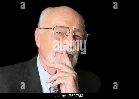An intelligent senior man with a thoughtful expression over a black background Stock Photo