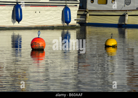 View of moored boats and reflections on canal basin, with mooring buoys Stock Photo