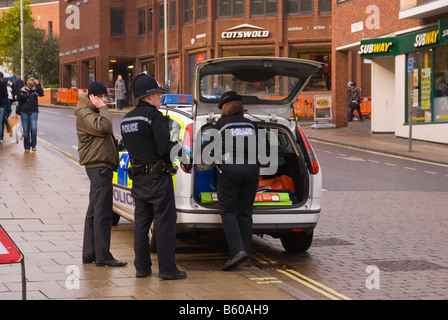 Two Uk police officers standing next to police car talking to possible plain clothed policeman or store detective in Norwich,Uk Stock Photo