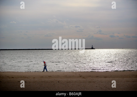 A lone man walks along a beach in New Haven Connecticut USA Stock Photo