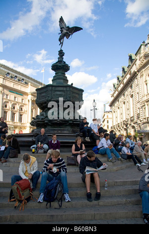 People sit on steps of the Shaftesbury Memorial Fountain in Piccadilly Circus London England Stock Photo