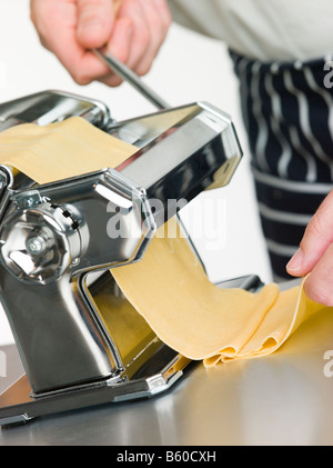 Fresh Egg Pasta being rolled in a Pasta Machine Stock Photo
