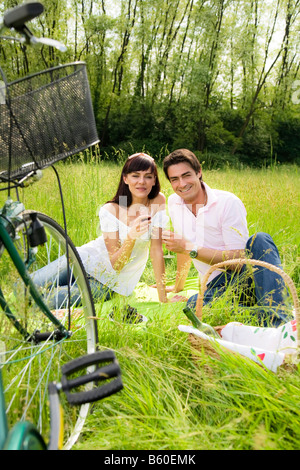 couple having a picnic in a park smiling and looking at the camera Stock Photo