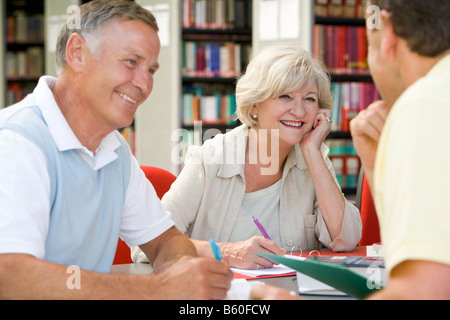 Three people in library writing in notebooks (selective focus) Stock Photo