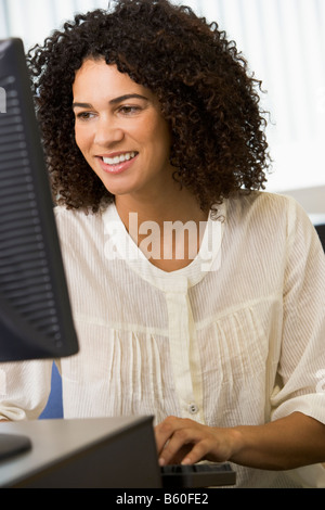 Woman sitting at a computer terminal typing (high key) Stock Photo