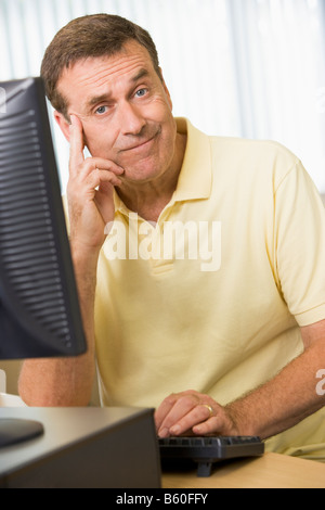 Man sitting at a computer terminal bored (high key) Stock Photo