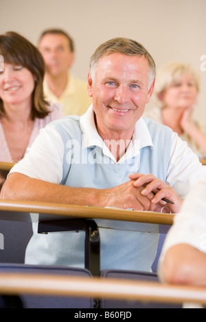 Man sitting in adult classroom with students in background (selective focus) Stock Photo