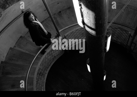 Young woman alone walking down the stairwell of a dark car park Stock Photo