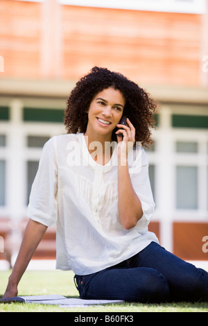 Woman on lawn of school using cellular phone Stock Photo