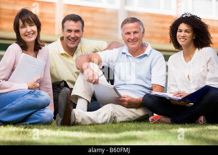 Adult students on lawn of school with notebooks Stock Photo