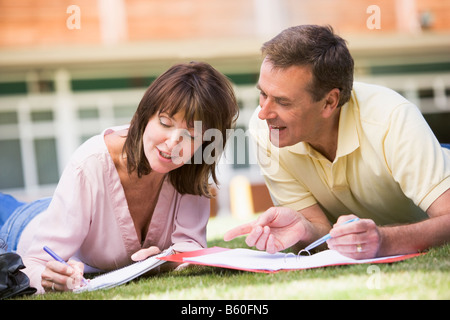 Adult students lying on lawn of school studying and talking Stock Photo