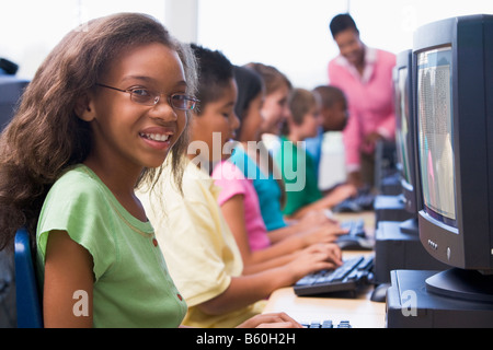 Six children at computer terminals with teacher in background (depth of field/high key) Stock Photo