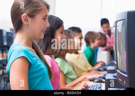 Six children at computer terminals with teacher in background (depth of field/high key) Stock Photo