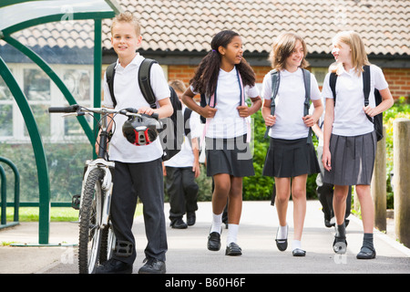 Students leaving school one with a bicycle Stock Photo