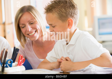 Student in class taking notes with teacher helping Stock Photo