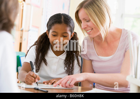 Student in class taking notes with teacher helping Stock Photo