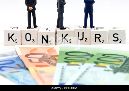 Cash notes in front of figures of businessmen standing on dice which spell the word KONKURS, bankruptcy, symbolic image for