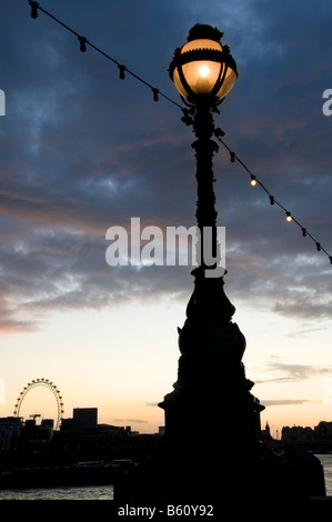 An ornate lamp on Victoria Embankment with London Eye in the background, London, England, UK Stock Photo