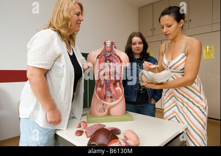 Geriatric care trainer teaching students with the aid of an anatomic training dummy Stock Photo