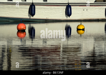 View of moored boat and reflections on canal basin, with mooring buoys Stock Photo