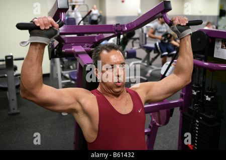 A 61-Year-old man works out in a gym. The man, who has a family history of Heart disease works out to improve his health.