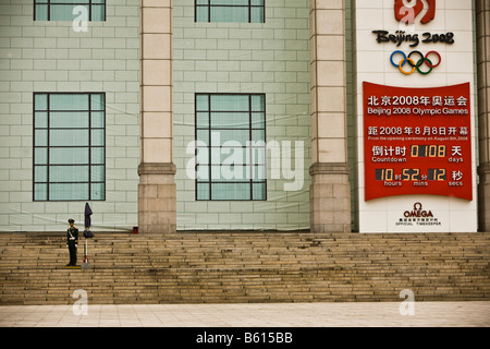 A soldier stands guard in front of a building showing the countdown to the 2008 Summer Olympics in Beijing in Beijing China Stock Photo