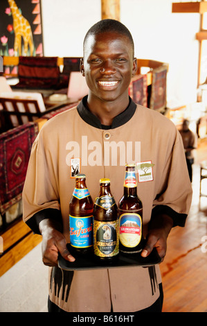 Waiter carrying the three most popular beers in Tanzania, Serengeti, Kilimanjaro and Safari, Lobo Wildlife Lodge Stock Photo