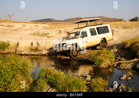 Vehicle crossing the course of a river, Serengeti National Park, Tanzania, Africa Stock Photo