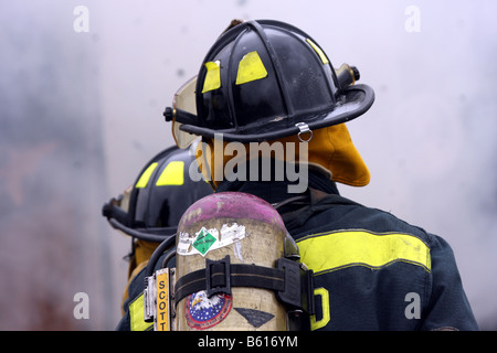 Two fire fighters surrounded by smoke while putting out a fire Stock Photo