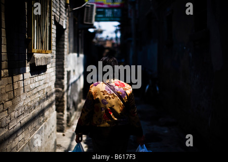 A woman walks down the narrow alleyway of a hutong in Beijing China in April 2008 Stock Photo