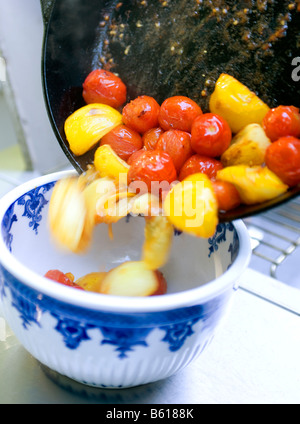 Cherry tomatoes red and yellow are seared in an iron skillet and then drizzled with red wine vinegar Stock Photo