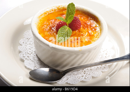 Creme Brulee dessert in small dish on a plate with spoon Stock Photo